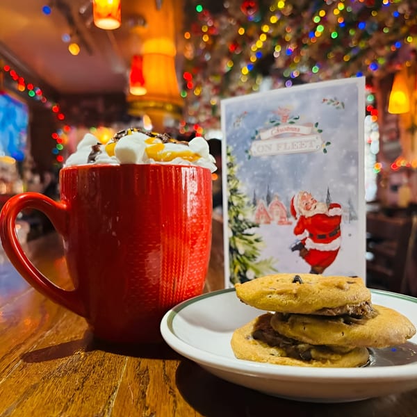 Red mug with whipped cream and cookies on a table with Christmas decorations at Ale Mary's.
